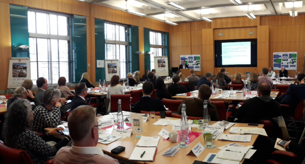 Photograph taken at Social Security Advisory Committee stakeholder event. It shows stakeholders sitting at a number of tables watching a presentation being delivered