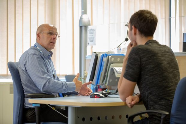 Work coach talking to a benefit claimant at a desk