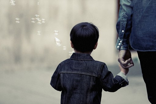 Parent holding hands with child who is blowing bubbles