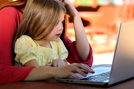 Image of adult working on laptop with child on lap