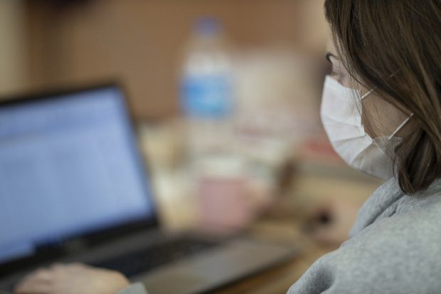 Female in protective face mask working on a laptop